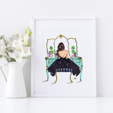 Framed artwork of a woman in a black dress sitting on a vanity mirror with flowers in a white vase.